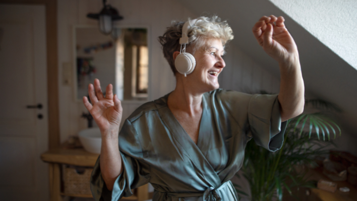 a senior lady listening to music and dancing with her headphones